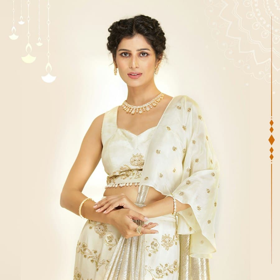 Woman in an ivory crop top and skirt set with a pearl necklace