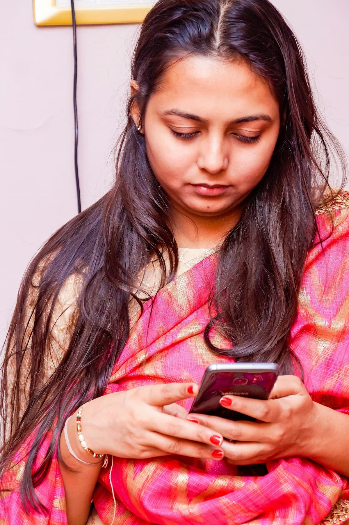 Young woman in a pink kurta reading customer messages on her phone