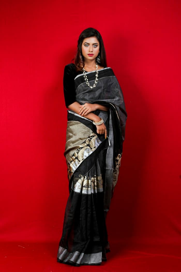 Woman in a charcoal and silver zari saree against a red backdrop